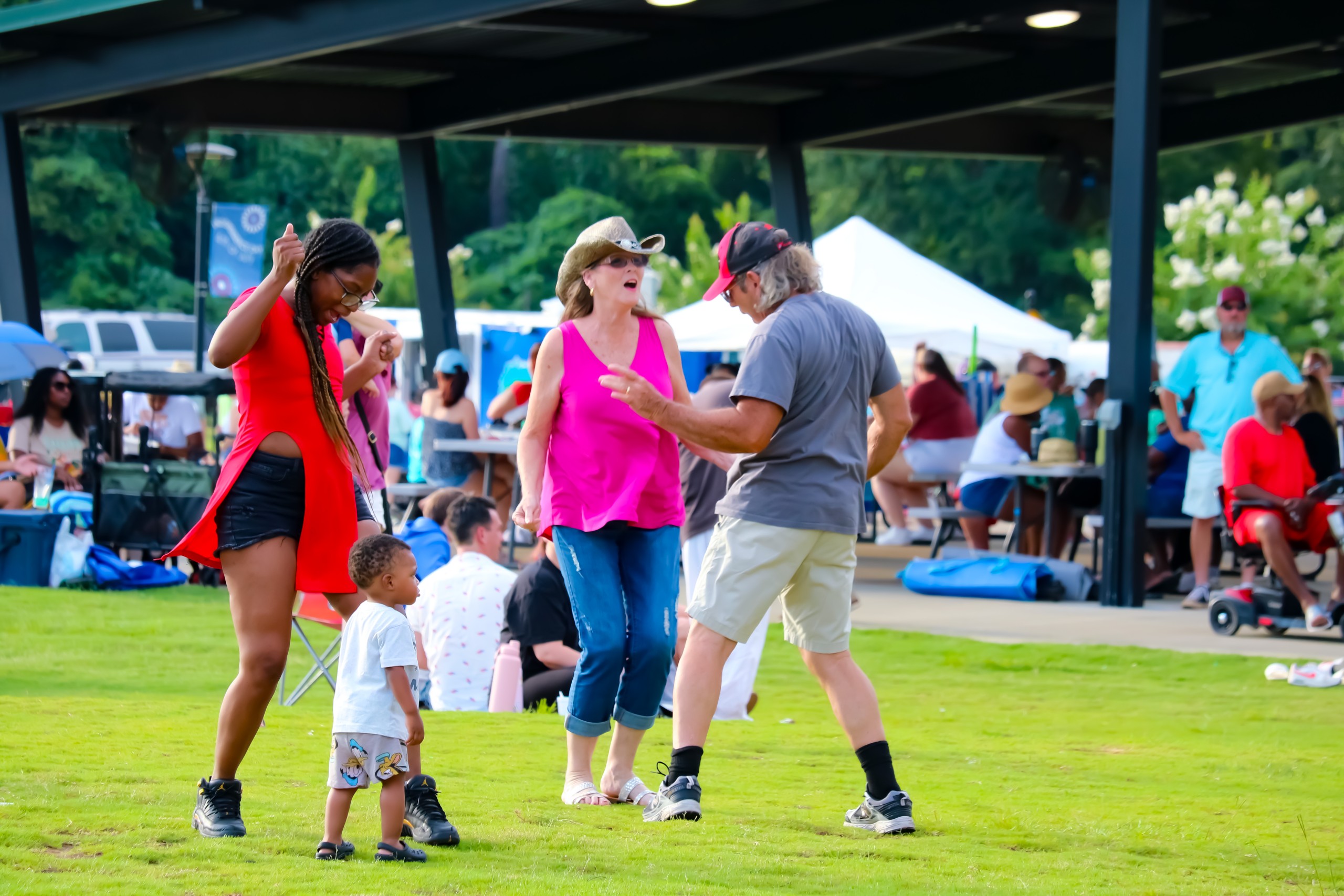 People dancing. Among then is a little boy standing next to a woman.