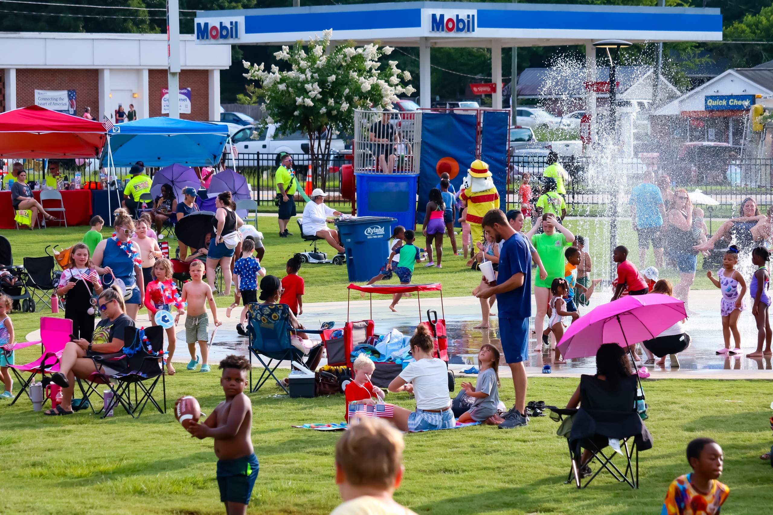 People sitting in lawn chairs and on blankets. Children are also seen playing.