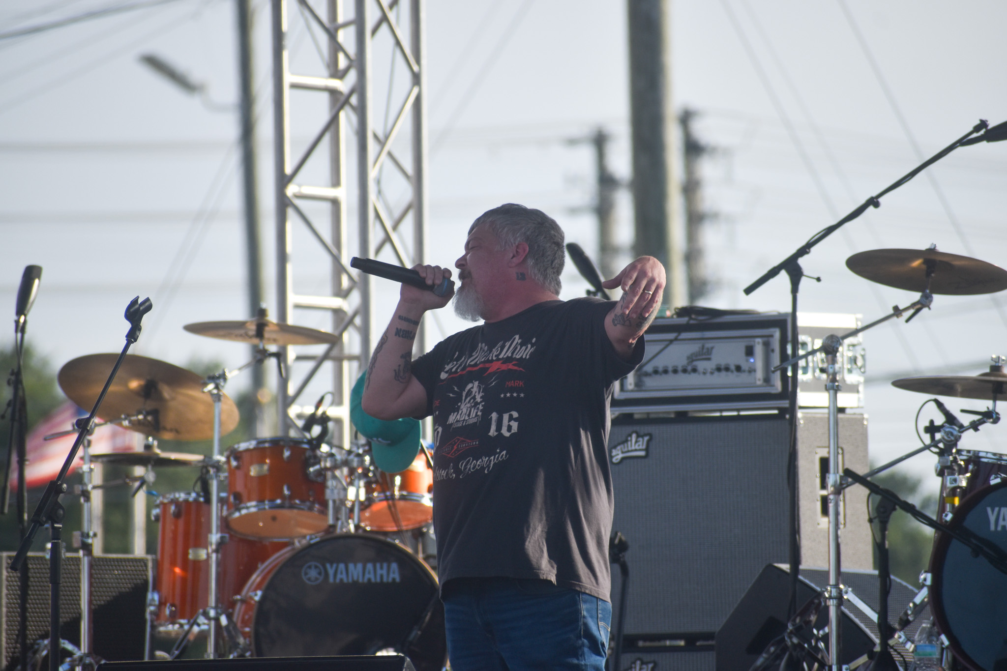 A man performing on stage. He is singing into the microphone.