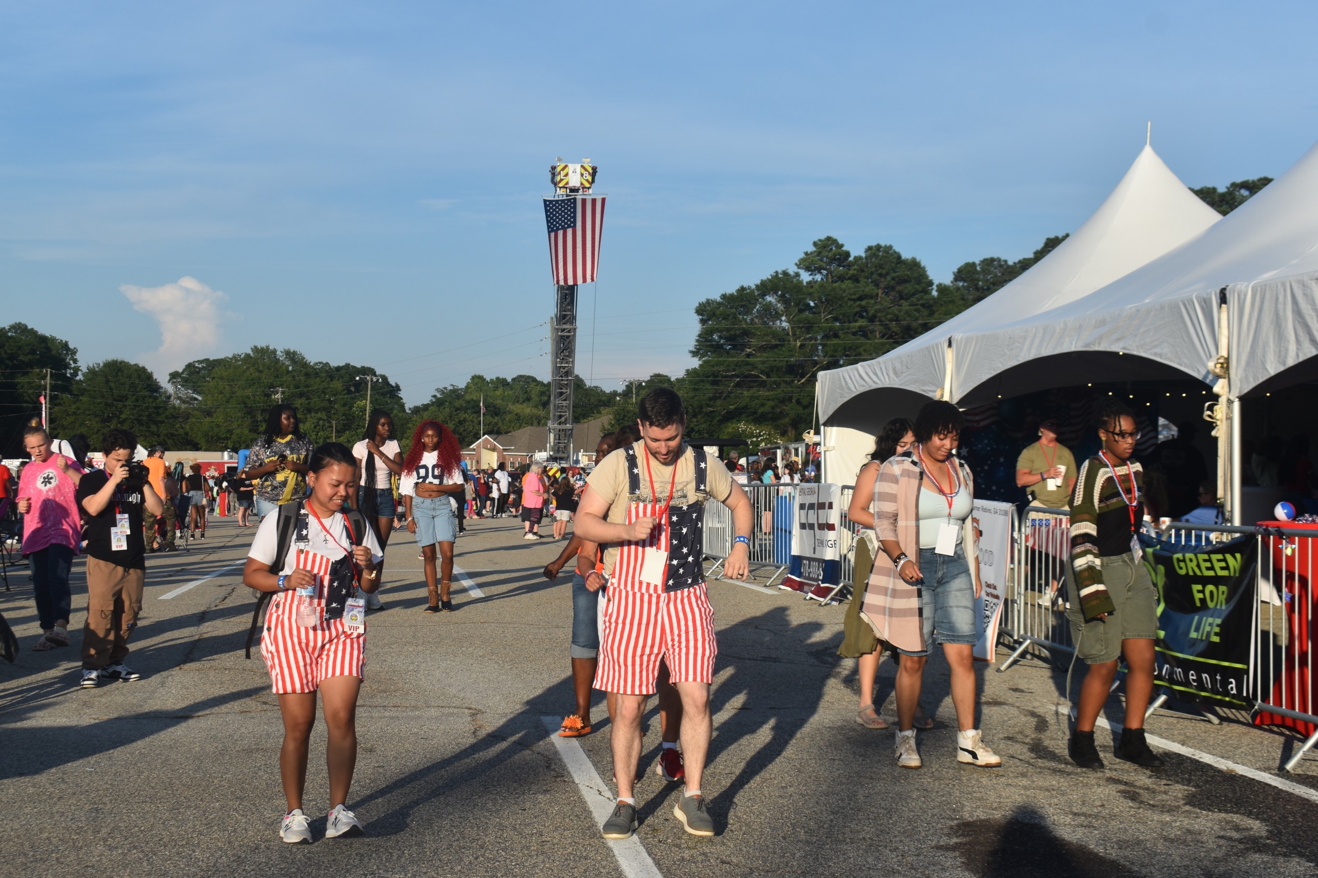 A group of people dancing. Two of them are wearing overalls which looks like the American flag.