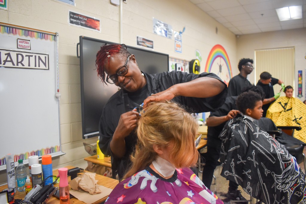 A woman giving a child a haircut. The child is sitting down in a chair.