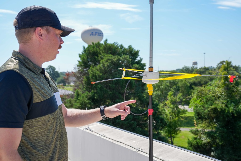 A man pointing at a yellow antenna.