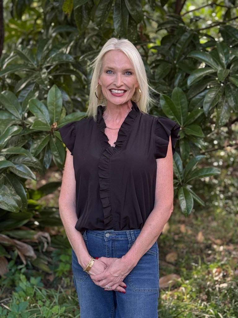 A blonde women with a black shirt smiling.