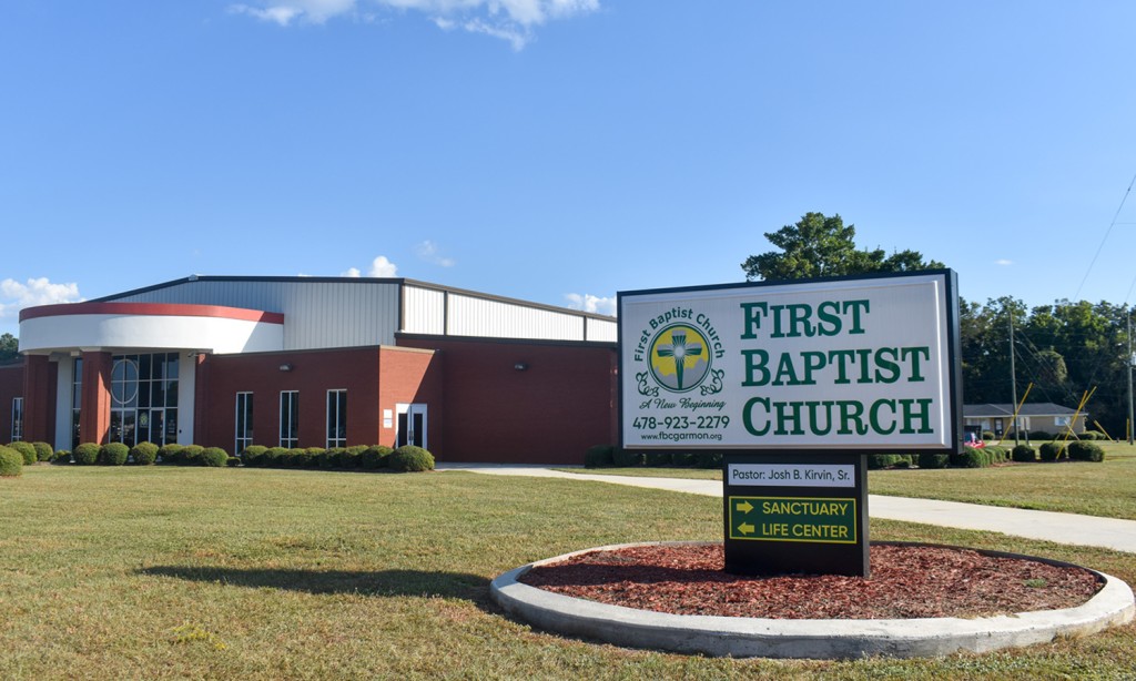 Photo of a church. On the side there is a white sign saying, "First Baptist Church" in green letters.