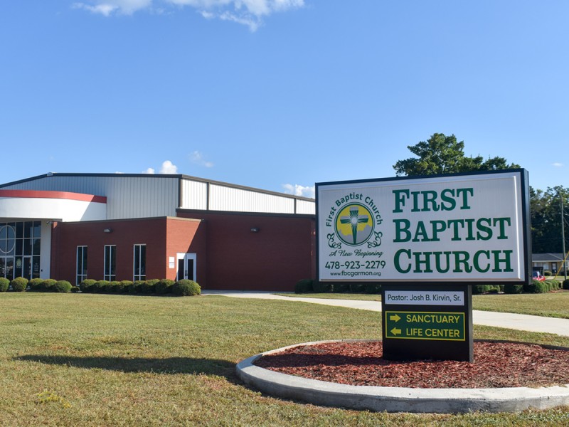 Photo of a church. On the side there is a white sign saying, "First Baptist Church" in green letters.