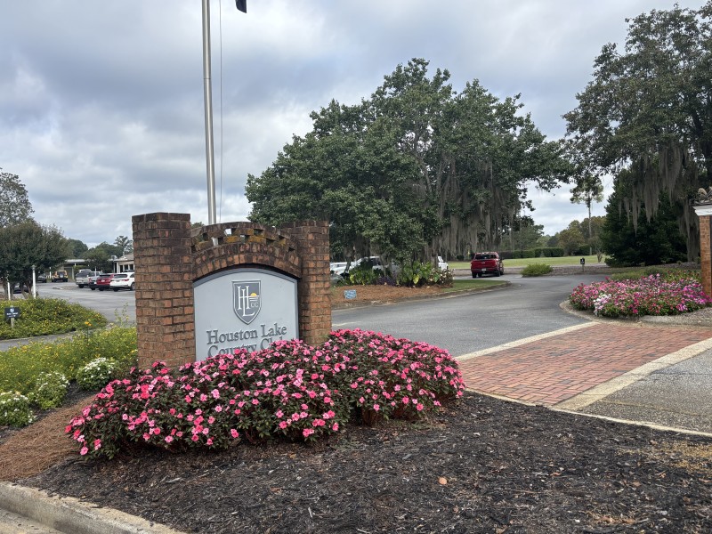 sign of the Houston Lake Country Club with bright pink flowers in front of it