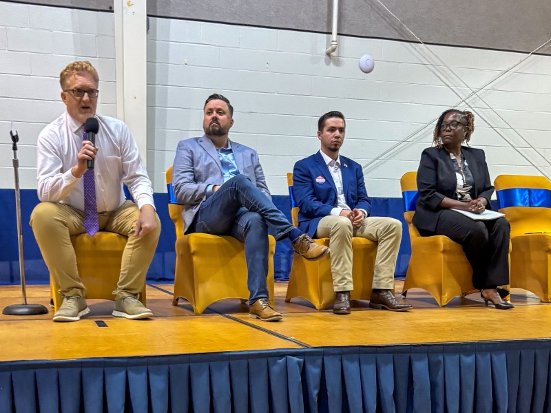 Three men and one woman sitting on a stage.