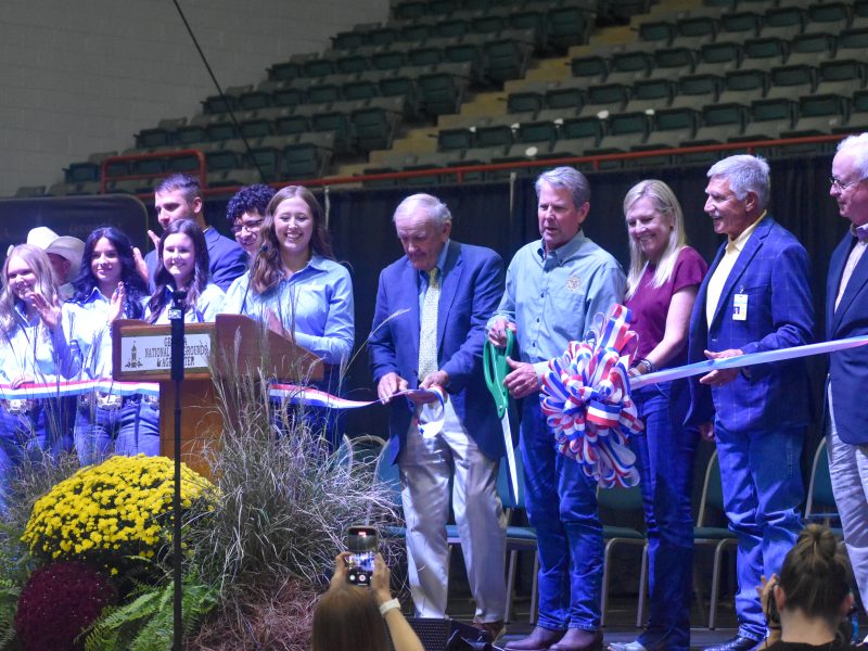 group of people standing on stage with a ribbon that had been cut