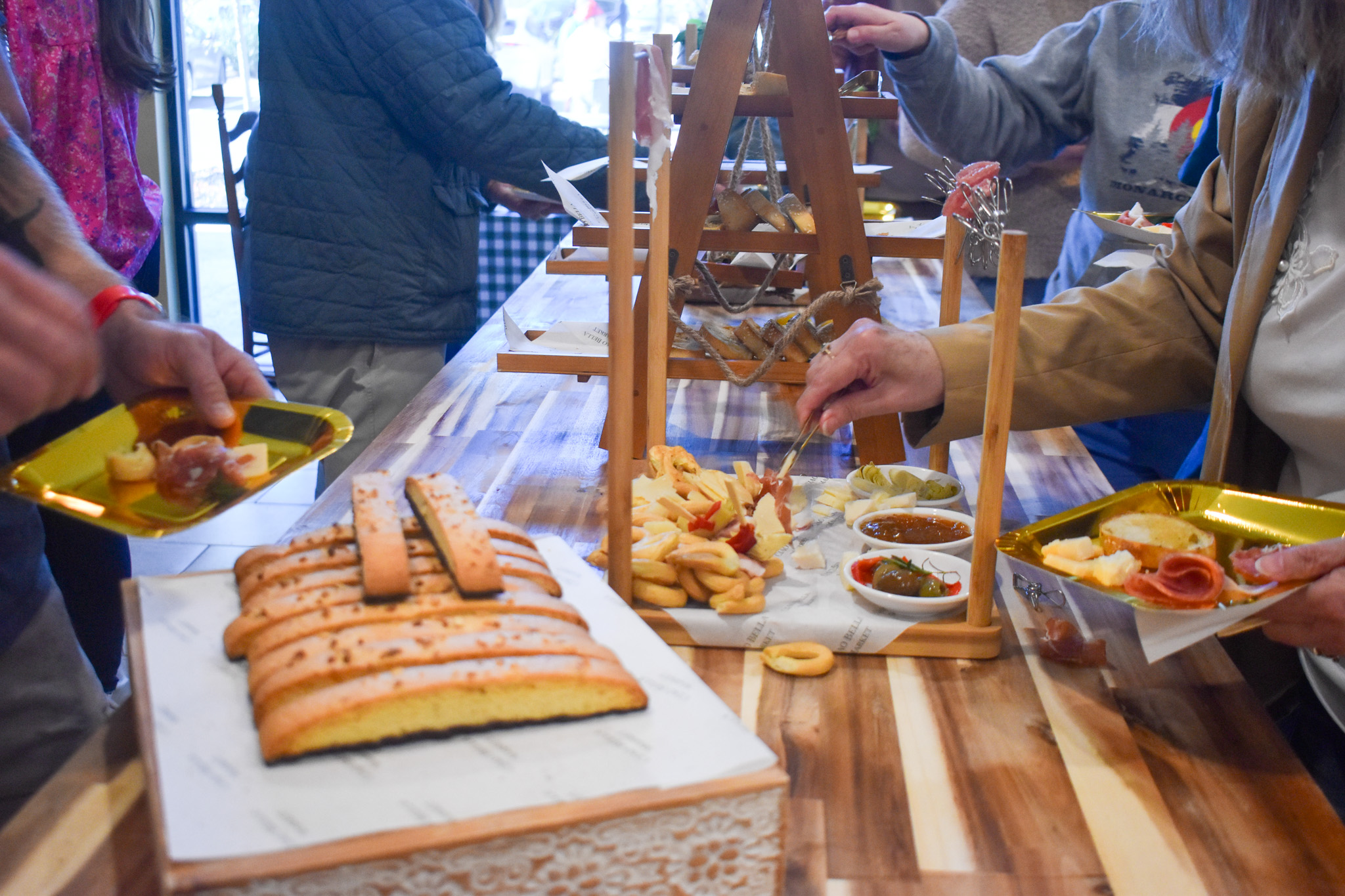 A table filled with food. One one plate there is cheese and sauce. On the left, there is a plate with Biscotti. 