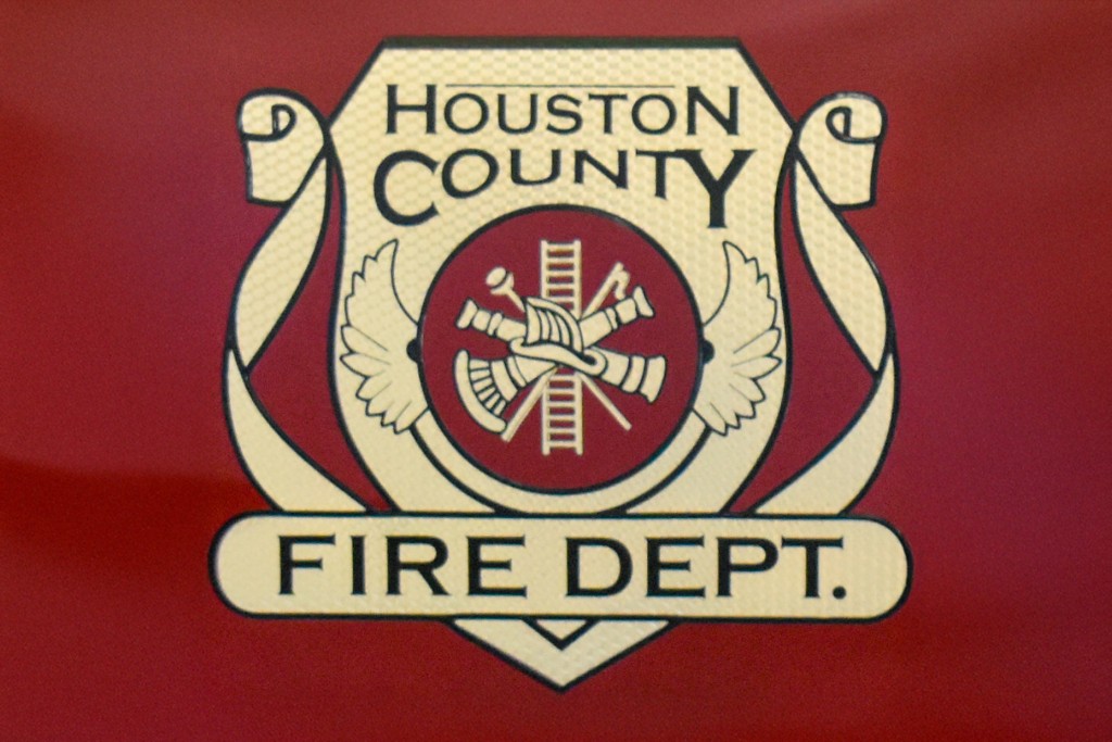 The Houston County Fire Department. It is gold with black words. There is a red background