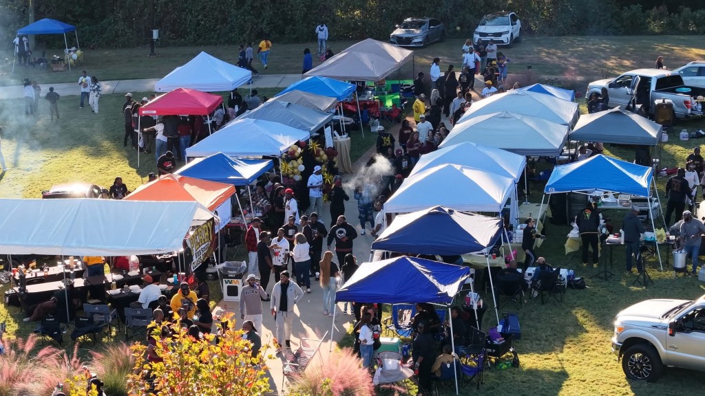 An overhead photo of people walking. Blue tents are set up around the area.