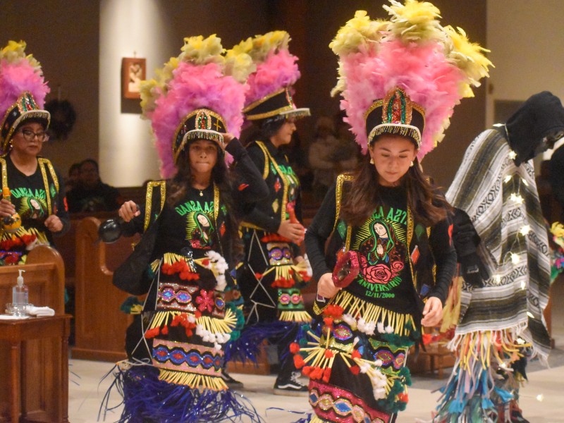 Two girls dancing. Both are wearing feathered hats and traditional Aztec clothing.