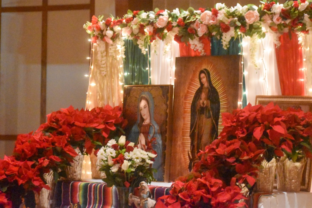 A shrine with red flowers and paintings of Our Lady of Guadalupe. 