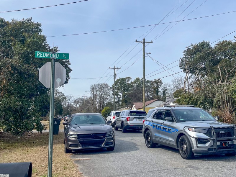 A silver police vehicle on the road. There is a street sign on the left.