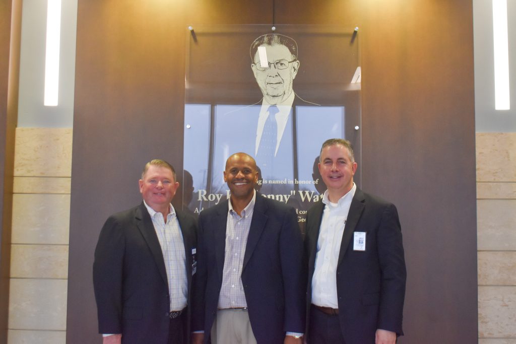 Three men in suits smiling. 