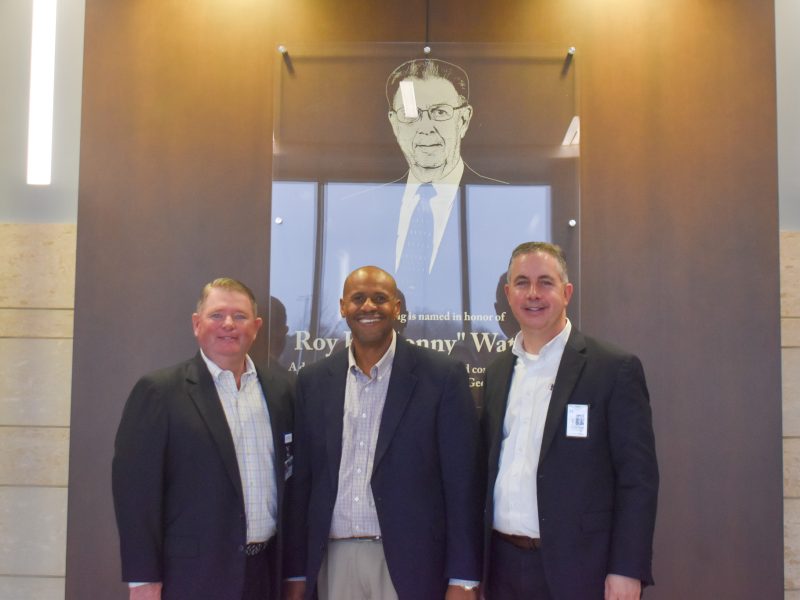 Three men in suits smiling.