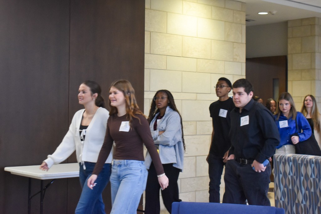 A group of students walking. The two girls in front of the line are smiling. 