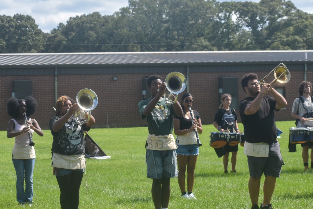 Students holding their gold trumpets. They are standing outside. 