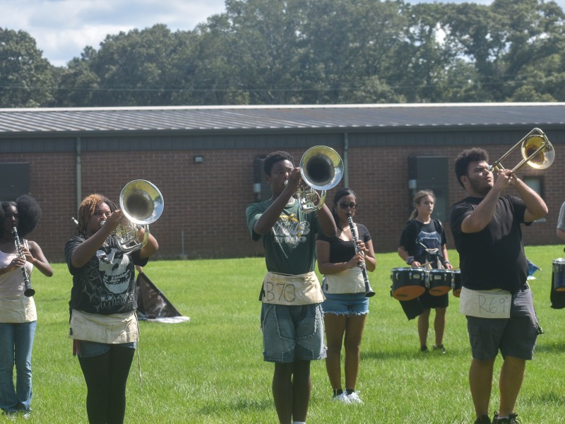 Students holding their gold trumpets. They are standing outside.
