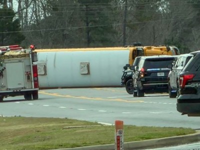 Black vehicles and a fire truck in front of a yellow school bus. It is in the middle of a street.