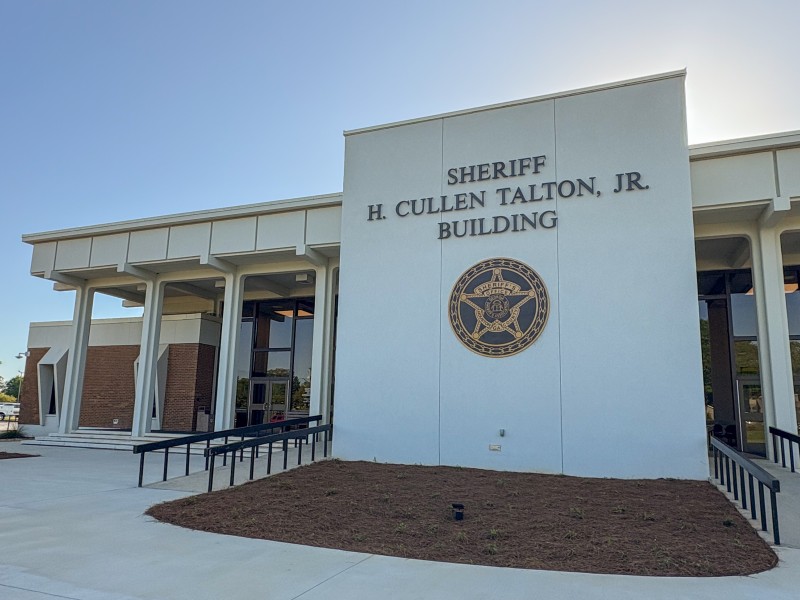 A white building with the Houston County Sheriff's Office symbol displayed on the front. Also in front of the building it says, "Sheriff H. Cullen Talton, Jr. Building."