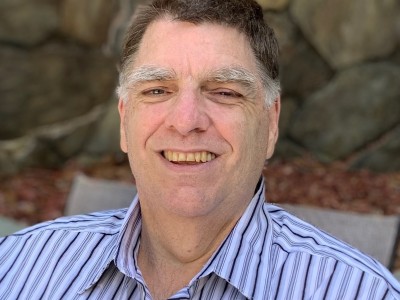 A man in a striped shirt smiling.