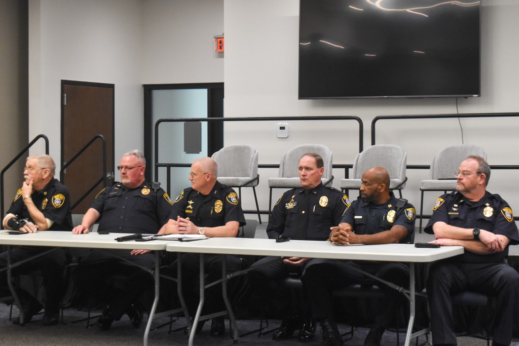 A group of men in police uniforms sitting behind a table. 