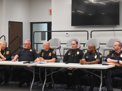 A group of men in police uniforms sitting behind a table.