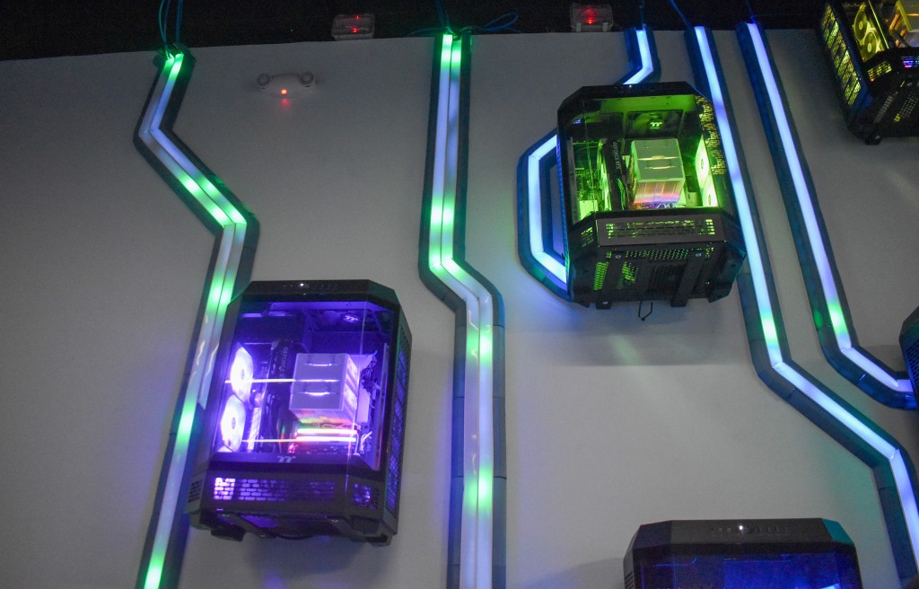 3D printers displayed on a wall. There is purple and green lighting.