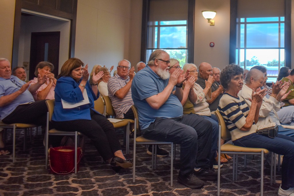 A group of people sitting on chairs clapping.