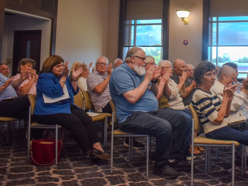 A group of people sitting on chairs clapping.