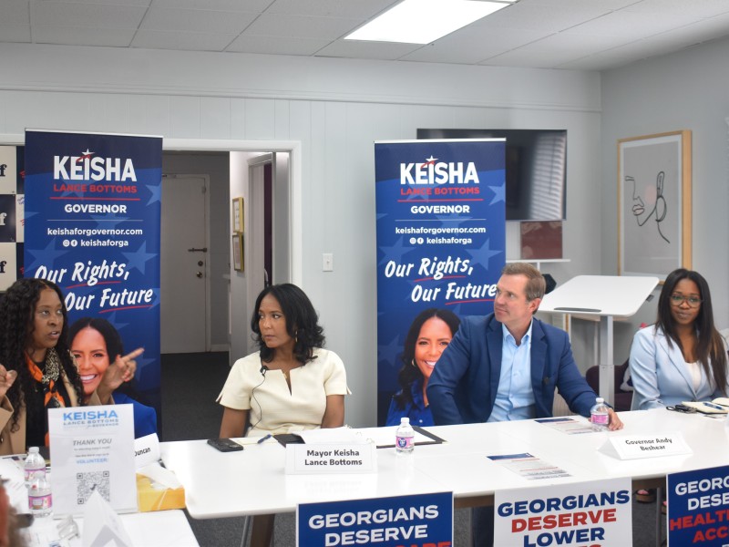 People sitting at a table. A woman on the far left is speaking.