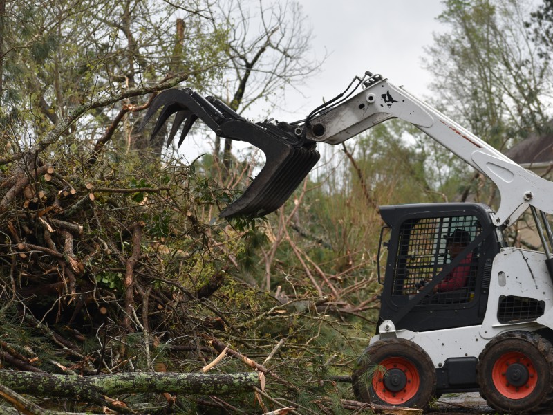 A white crane picking up tree debris.