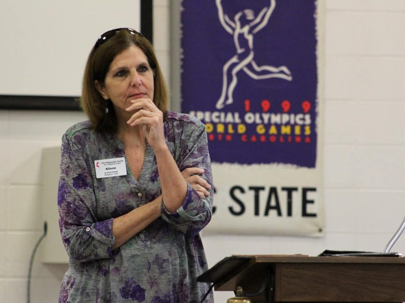 A older white woman with shoulder length brown hair listens.