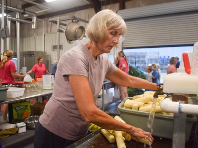 An older woman in a purple shirt washing her hands.