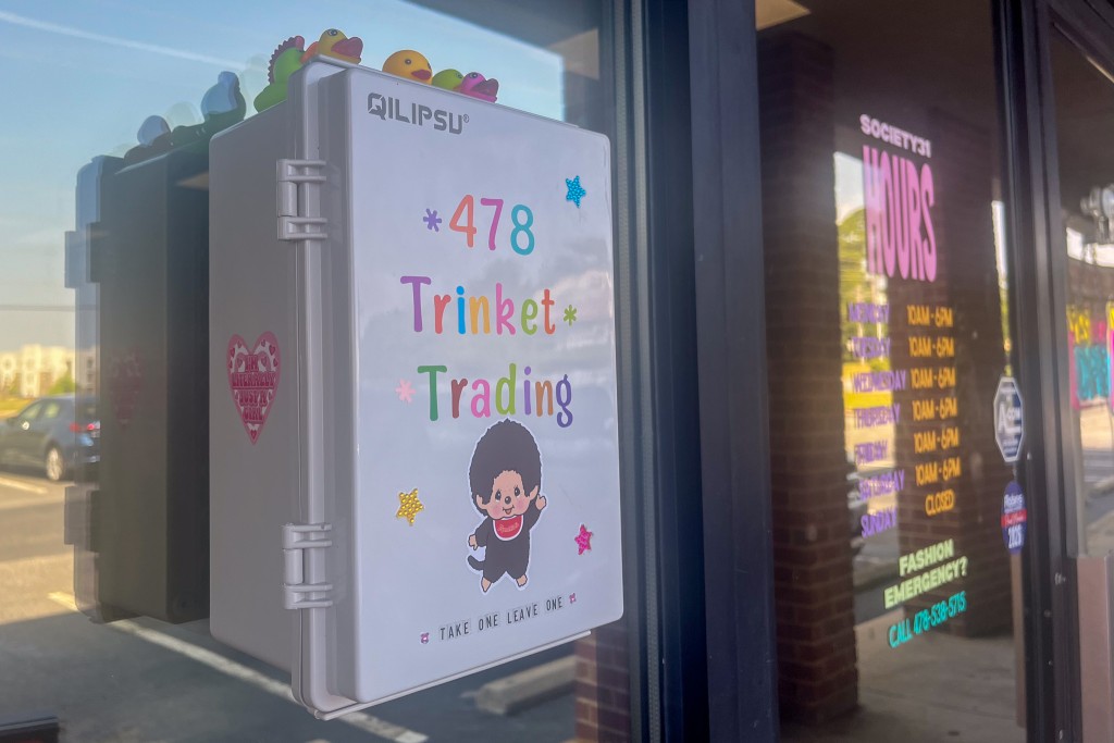 White box decorated with colorful stickers placed on a store window. 