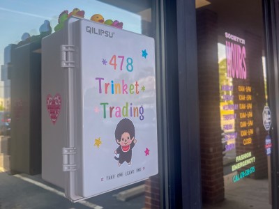 White box decorated with colorful stickers placed on a store window.