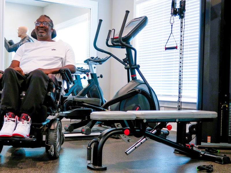A man in a wheelchair posed next to exercise equipment.