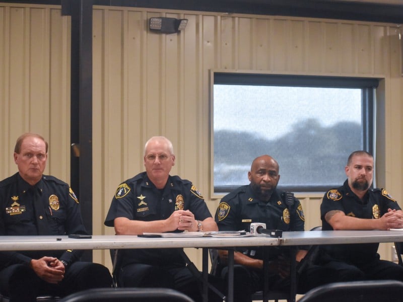 A group of men sitting at a table. They are wearing police uniforms.
