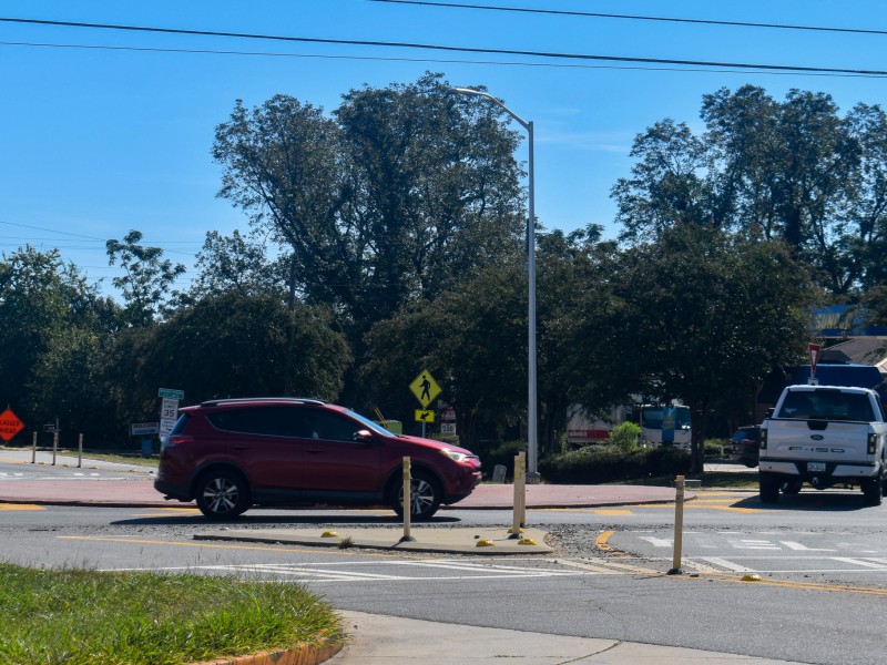 A white truck and a red car driving around a roundabout.