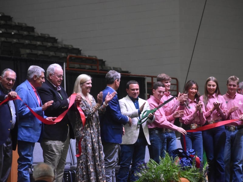 A group of people smiling. A ribbon is in front of them.