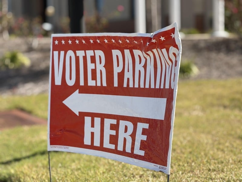 Red sign with white print and a white arrow directs voters where to park during early voting.